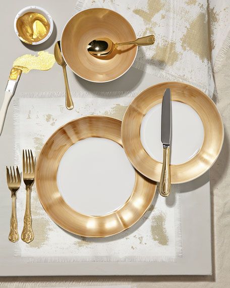 the table is set with gold plates and silverware