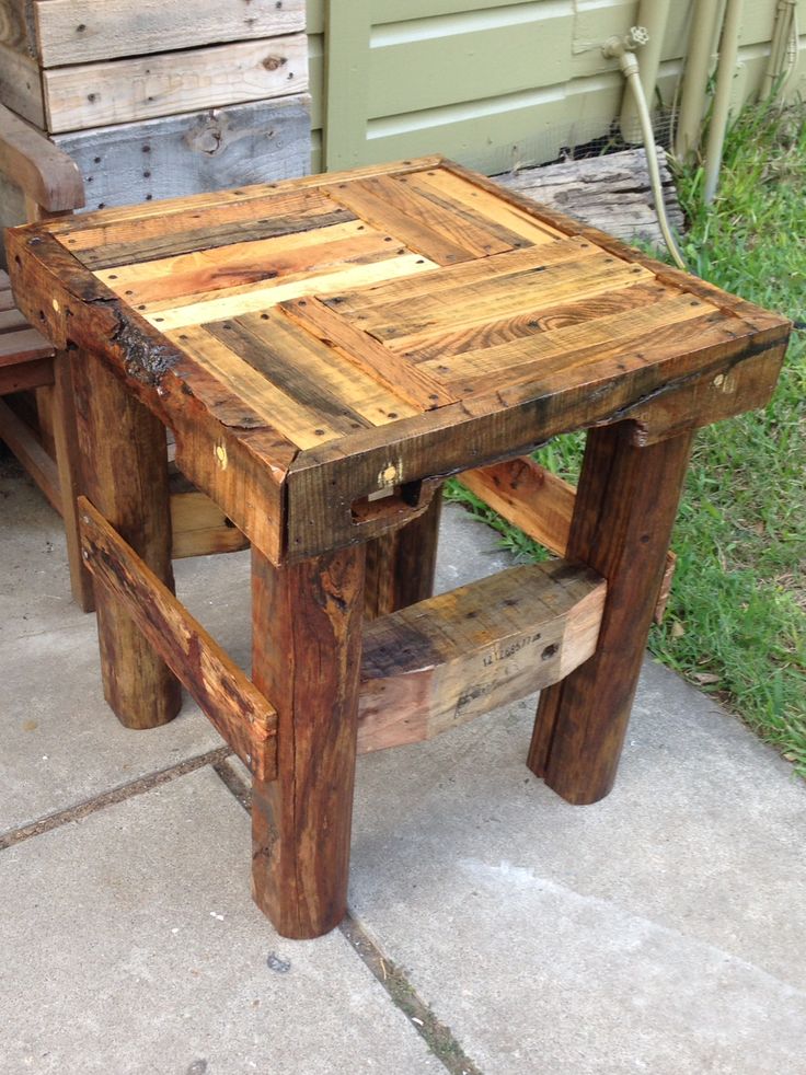 a small wooden table sitting on top of a cement floor next to a green door