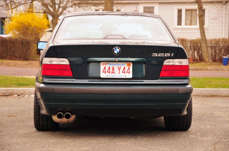 the back end of a black car parked in front of a house