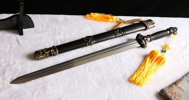 three different types of swords on a white cloth with gold accents and tassels