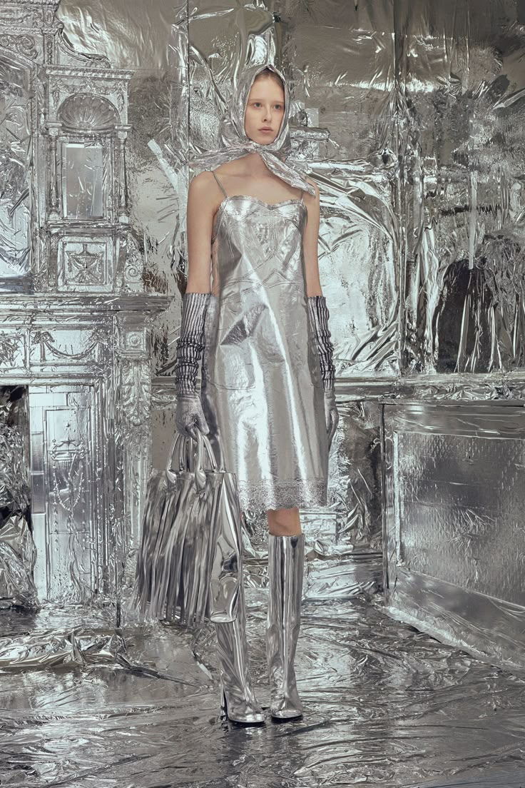 a woman in silver is walking down the runway