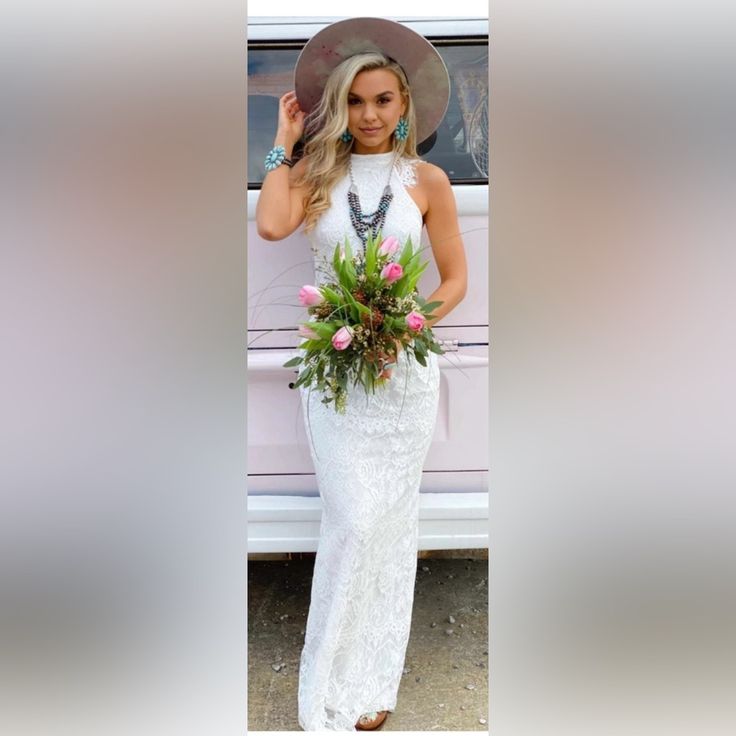 a woman in a white dress and hat standing next to a car with flowers on it