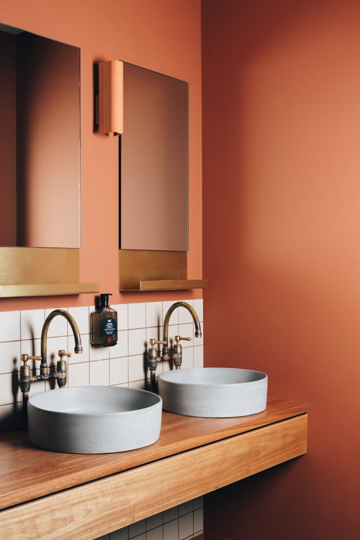 two sinks in a bathroom with orange walls