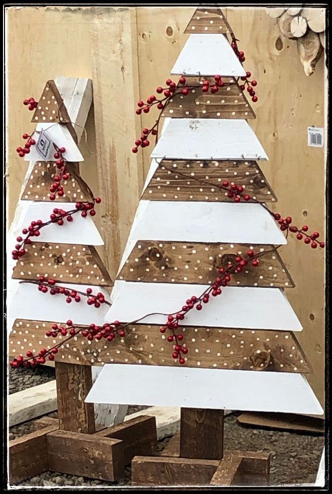 three wooden christmas trees with red berries on them, sitting in front of a wall