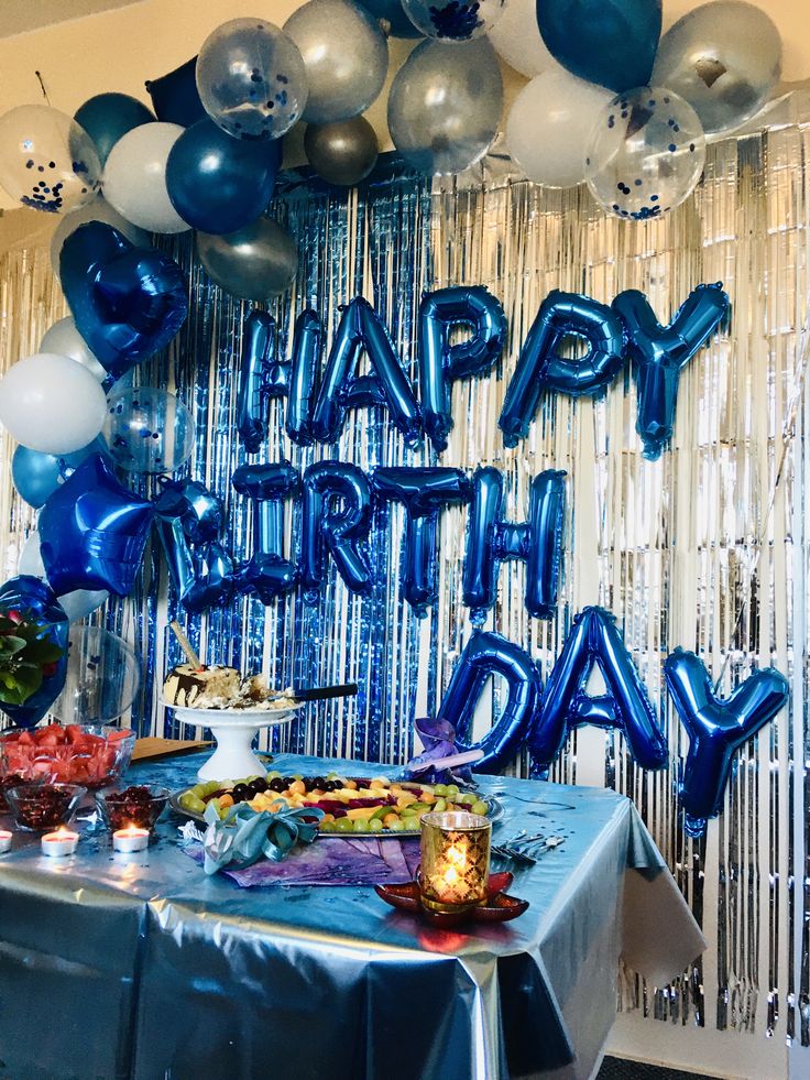 a birthday party with blue and silver balloons, streamers and confetti on the table