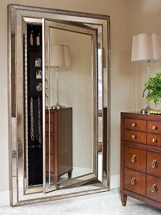 a large mirror sitting on top of a dresser next to a lamp and wooden drawers