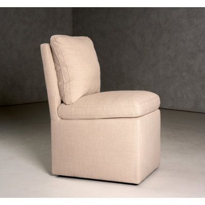 a beige chair with a pillow on it's back and seat cushion in the corner