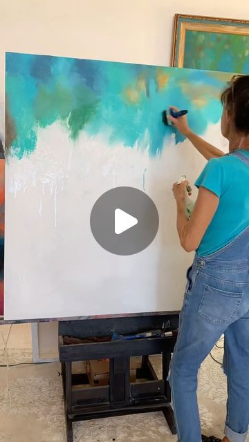 a woman is painting on a large canvas