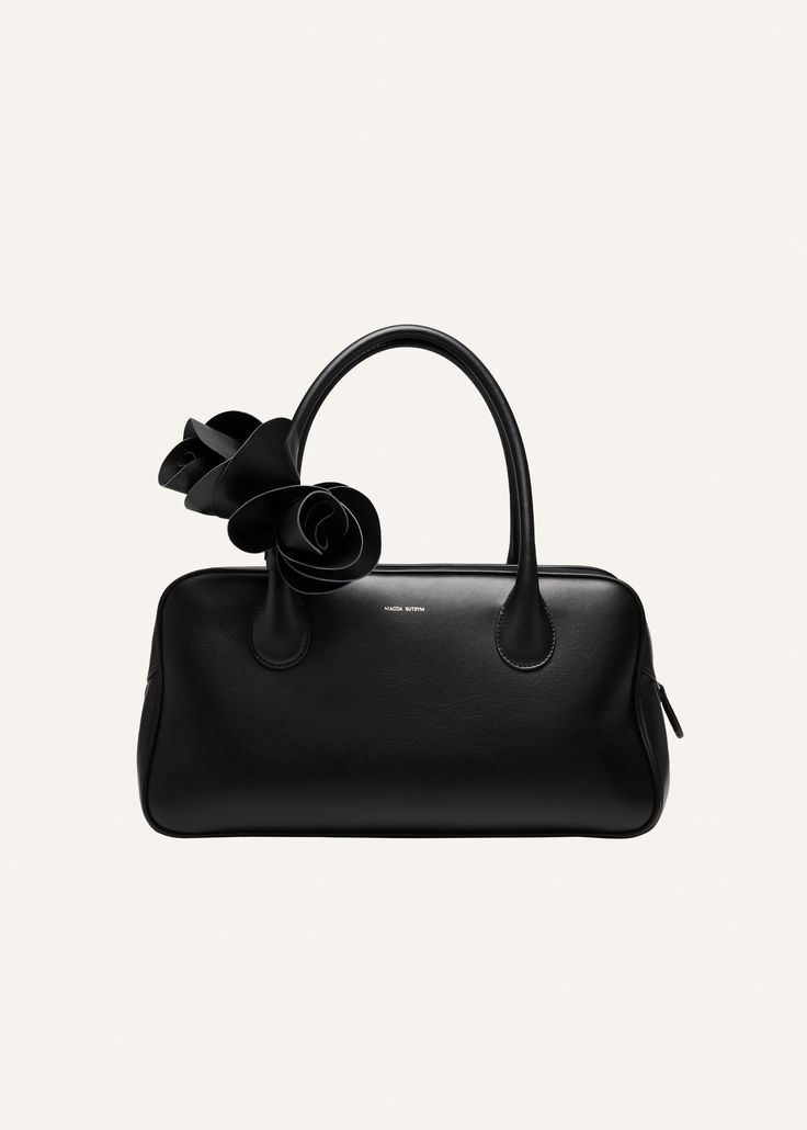 Introducing the Brigitte handbag. Inspired by the nostalgia of 90's while deeply rooted in Magda's family heritage. Its elegant silhouette, the roomy interior, two top handles and top zipper have been thoughtfully crafted in Italy. Adding a touch of on-brand dreaminess is the leather flower embellishment. Meticulously arranged and fixed onto the bag's handle. Stylish Leather Bags, Large Leather Tote Bag, Leather Flower, Magda Butrym, Family Heritage, Large Leather Tote, Bowling Bags, Leather Flowers, Online Fashion Stores