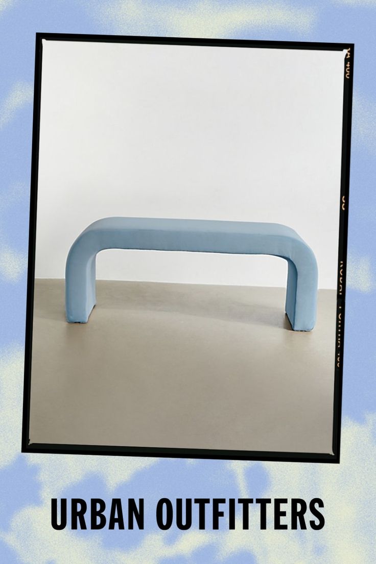 a blue bench sitting in front of a white wall with the words urban outfitters on it