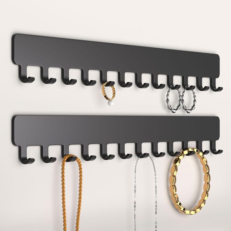 two black wall mounted hooks with gold and silver rings hanging on it's sides