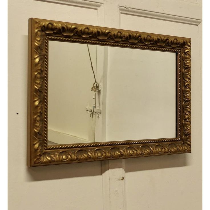 a gold framed mirror hanging on the wall