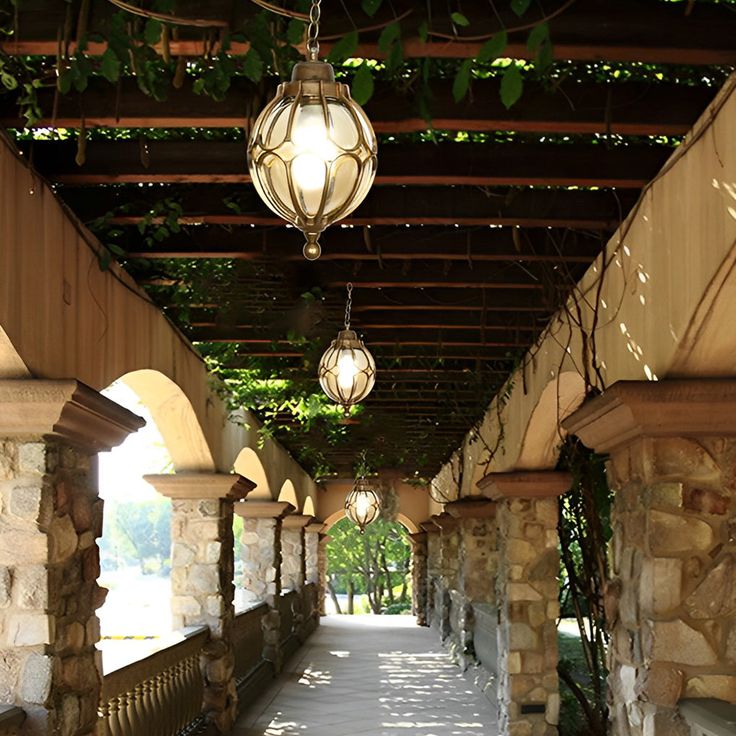 the walkway is lined with stone pillars and lanterns hanging from the pergolated roof