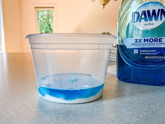 a bottle of dawn ultra and a container of blue liquid on a kitchen countertop