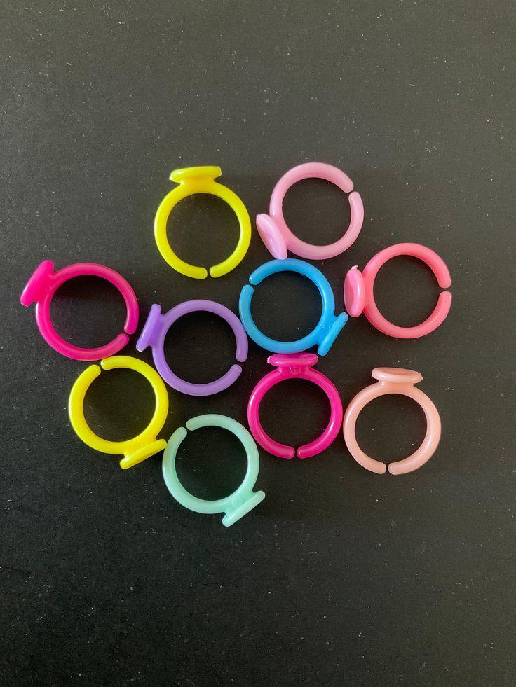 six pairs of pink, blue, and yellow scissors on a black surface with one pair missing