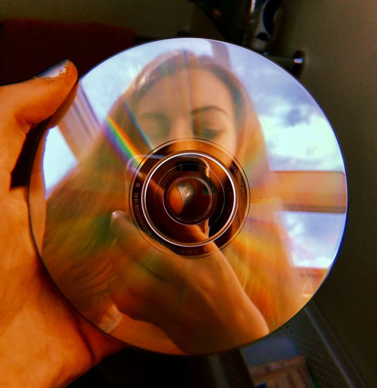 a person holding a cd in their right hand and looking at the disc on her left