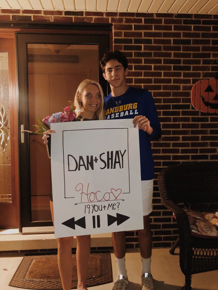 a man and woman standing next to each other holding a sign