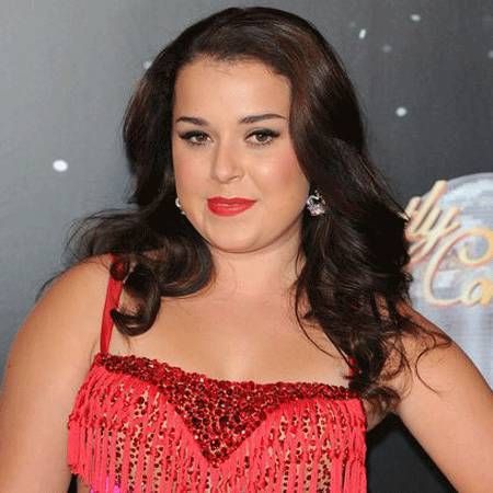 a woman with long dark hair wearing a red dress and diamond earrings, posing for the camera