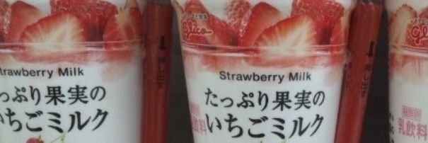 three cups with strawberries on them are lined up in a row and labeled strawberry milk