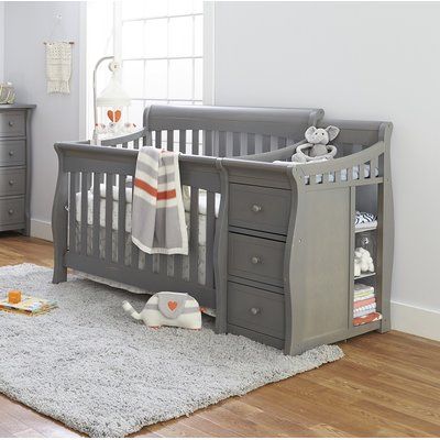 a baby crib with two drawers and a stuffed animal on the floor next to it