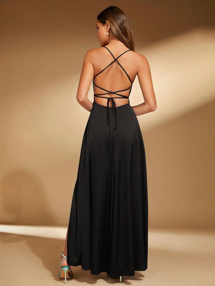 the back of a woman wearing a long black dress with cross straps and high slits