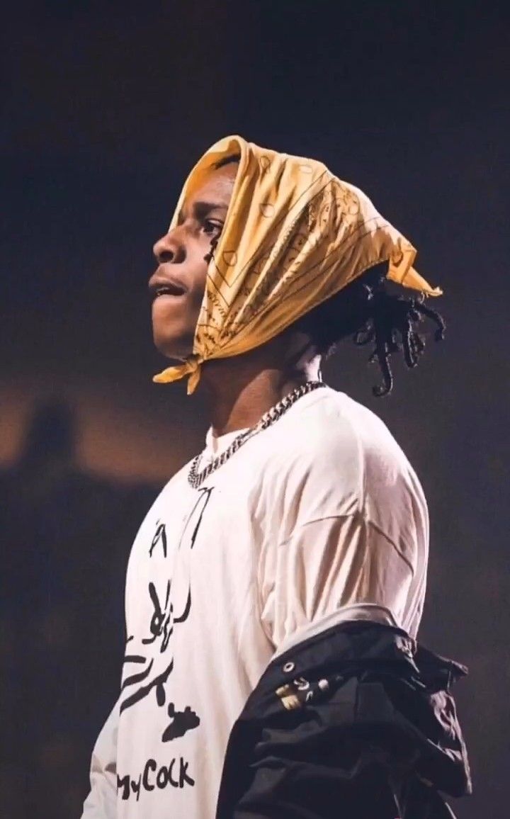 a woman with a gold head scarf on her head standing in front of a dark background