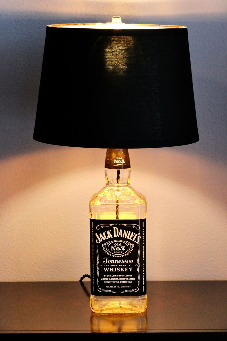 a lamp that is on top of a table with a bottle in front of it