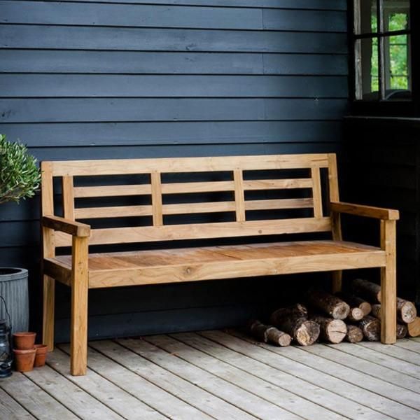 a wooden bench sitting on top of a wooden deck next to a pile of logs