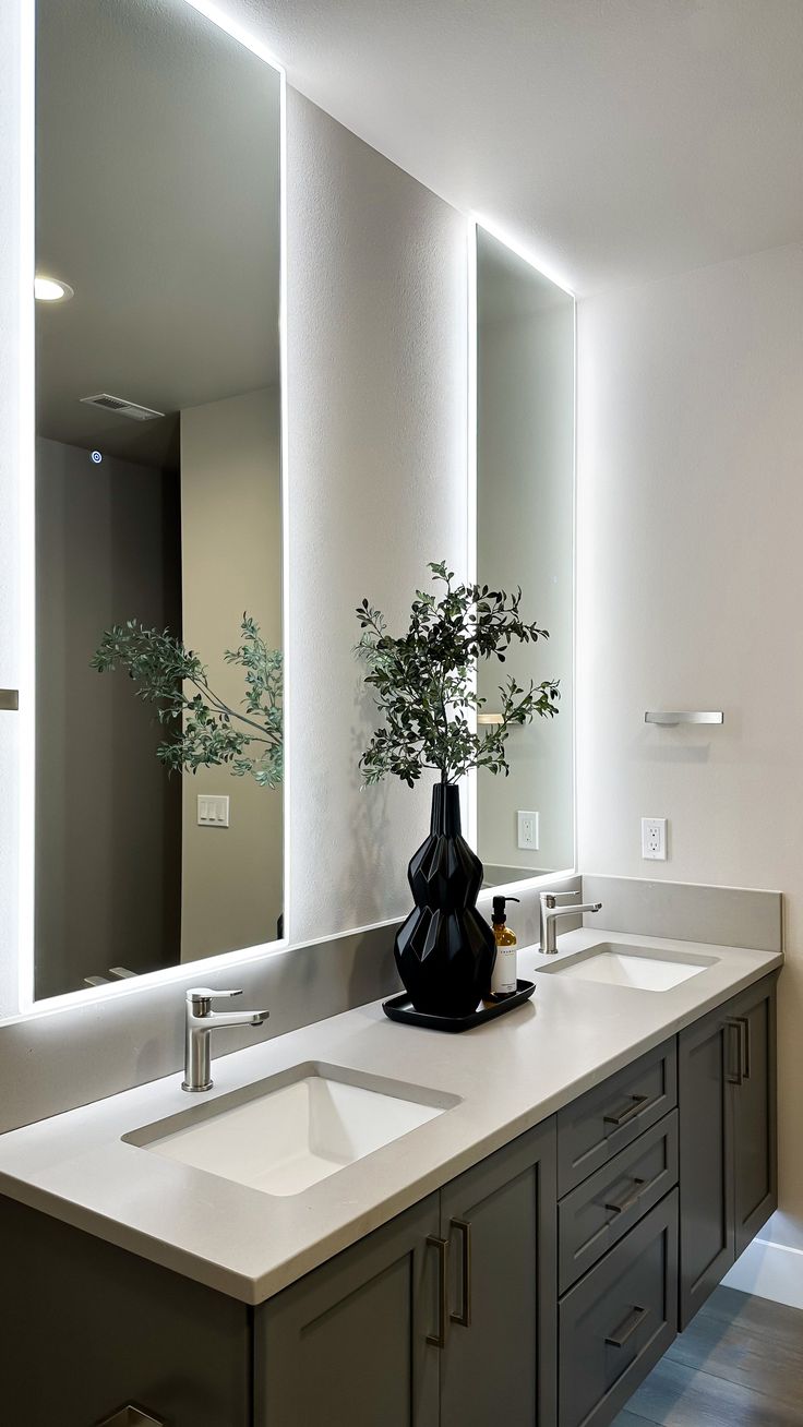 a bathroom with double sinks and large mirrors on the wall above them is illuminated by lights