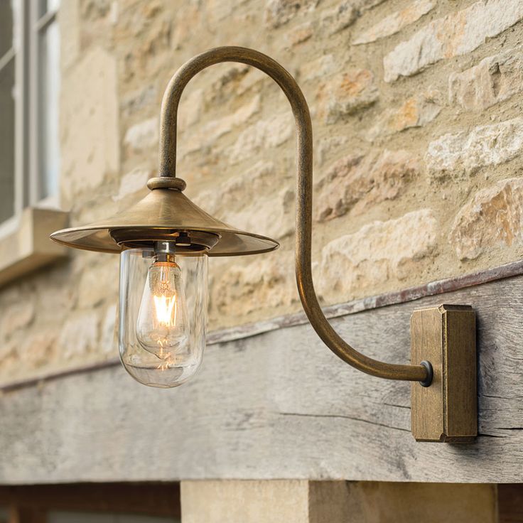 an old fashioned light fixture on the side of a building with a brick wall behind it