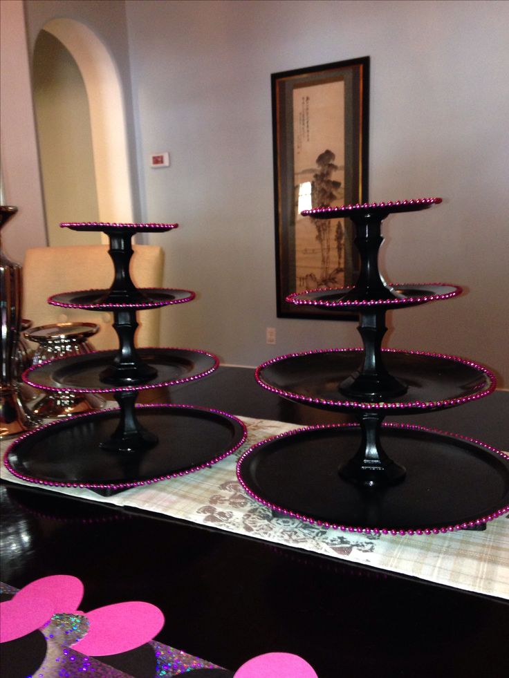 three black trays with pink beaded trim on them sitting in front of a mirror