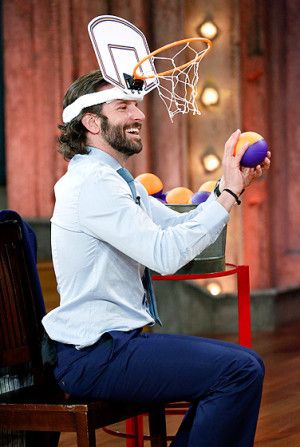 a man sitting in a chair with a basketball hoop on his head while holding balls