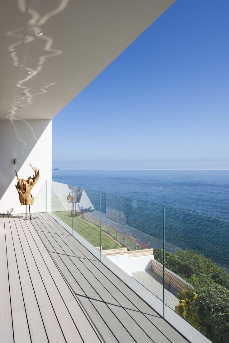 a balcony overlooking the ocean with an animal statue on it's back end and glass railings