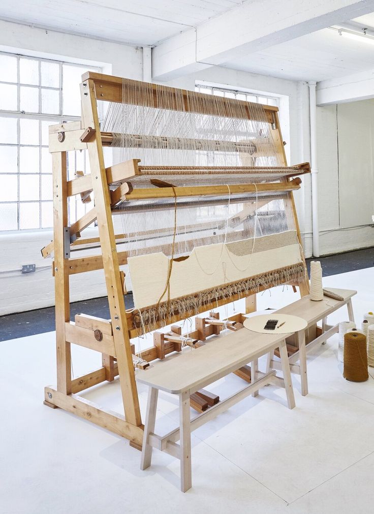 an old weaving machine is sitting in the middle of a room with two wooden benches