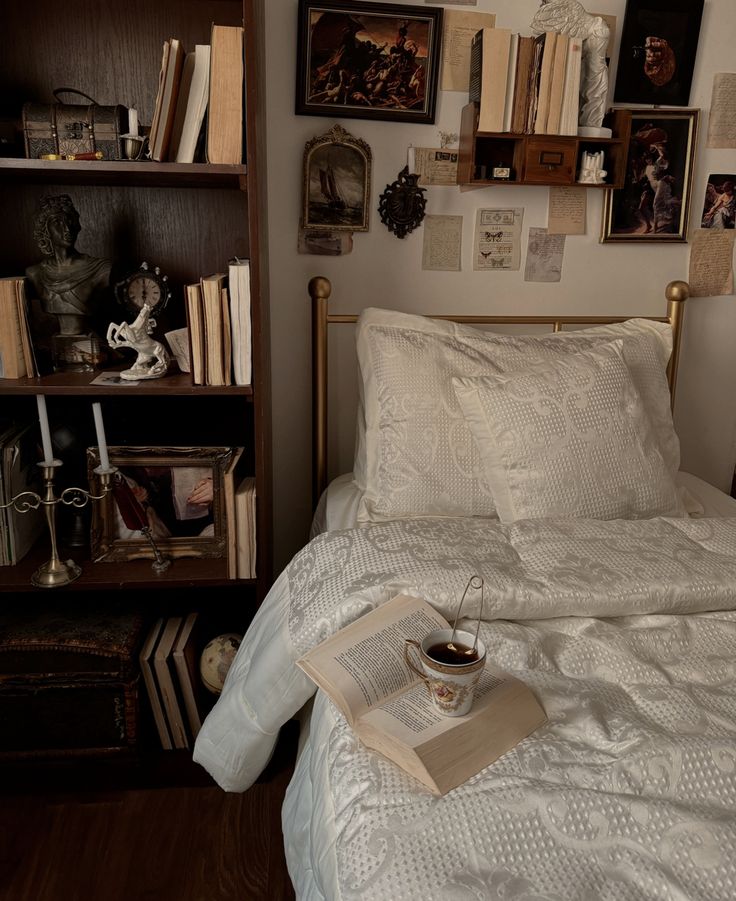 a book and cup on a bed in a room with bookshelves above it