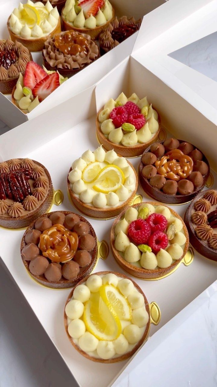 there are many desserts in the box on the table and one is decorated with fruit