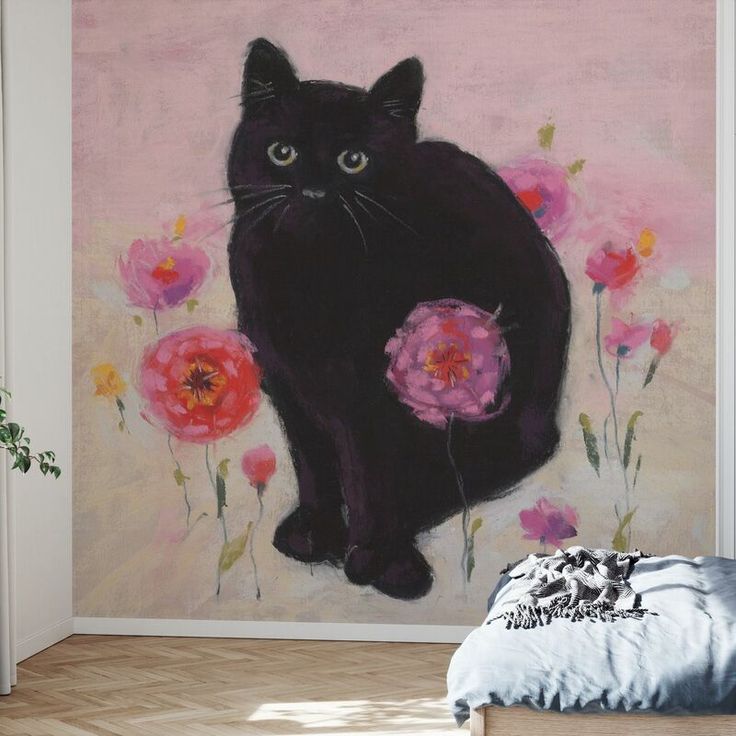 a black cat sitting on top of a bed in front of a wall with flowers