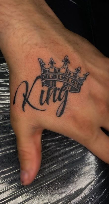 a person's hand with a tattoo on it that says king and crown in black ink