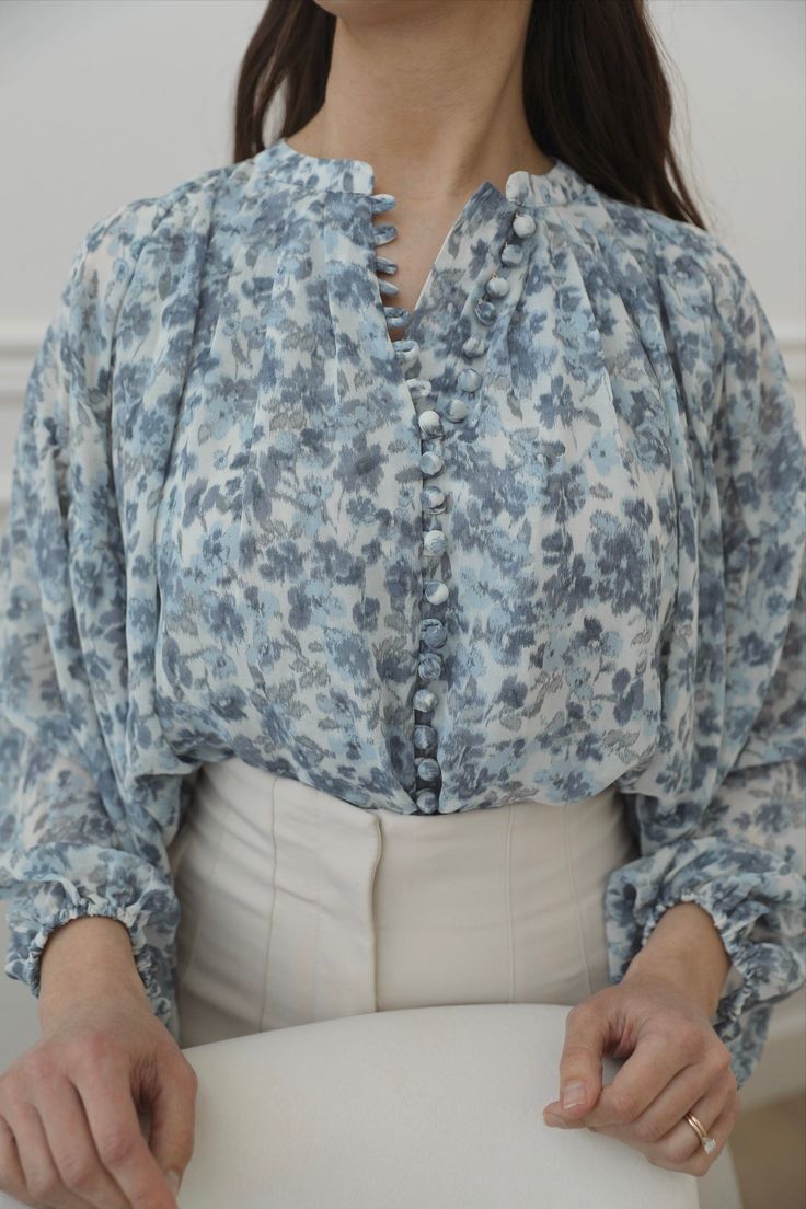 The blue floral blouse is a stylish and elegant long sleeve button down top. The beautiful floral print in shades of blue adds a touch of femininity to the blouse, making it perfect for any occasion. The comfortable and breathable material of the blouse ensures that you can wear it all day long without feeling uncomfortable. Pair it with your favorite pair of jeans or skirt for a chic and sophisticated look. blue floral print pattern balloon sleeves button placket elasticized band at waist shirr Blouse And Trousers Outfit, Curvy Date Night Outfit, Satin Blouse Outfit, Posh Clothing, Air Clothes, Feeling Uncomfortable, Outfit Ideas Spring, Blue Floral Top, Spring Blouses