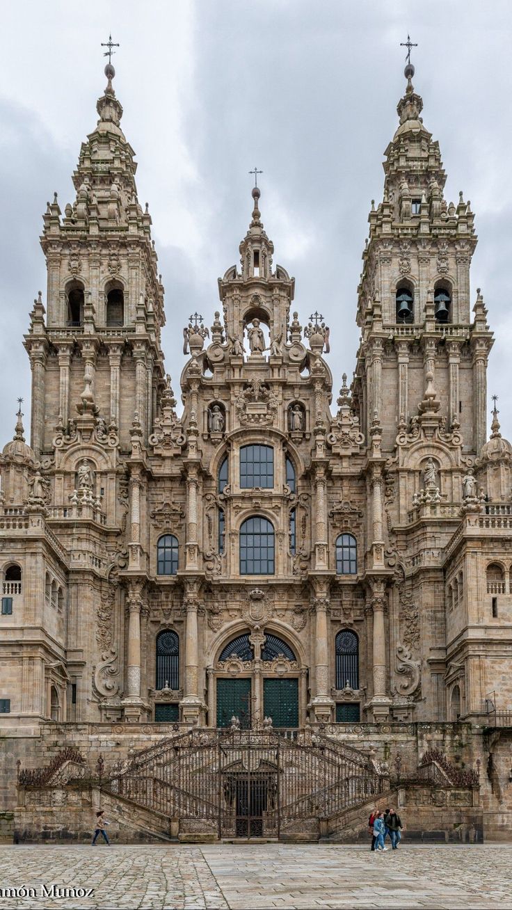 an ornate building with three towers and two people standing in front of the entrance to it