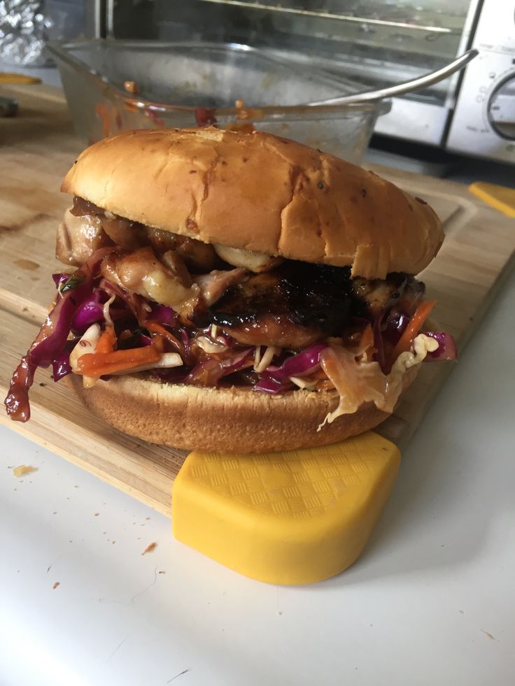 a pulled pork sandwich sitting on top of a cutting board