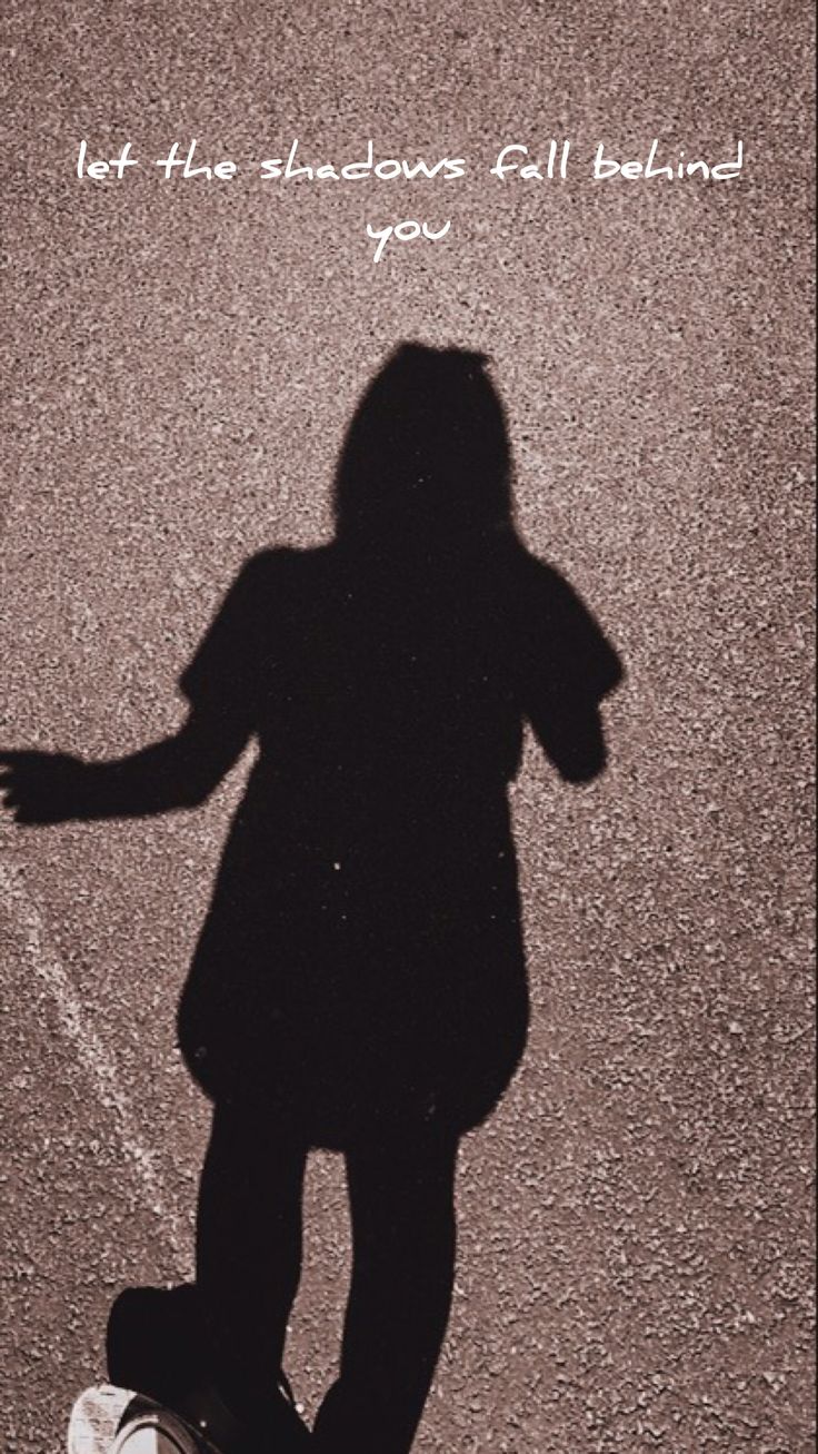 the shadow of a person riding a skateboard on a paved surface with words above it