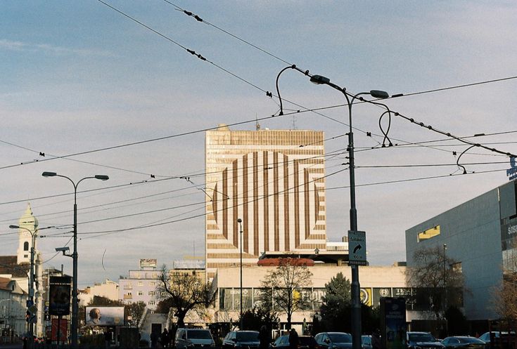 cars are driving down the street in front of tall buildings and power lines above them