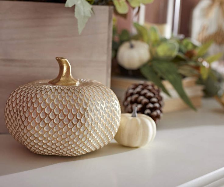 a white pumpkin sitting on top of a table next to pine cones and other decorations