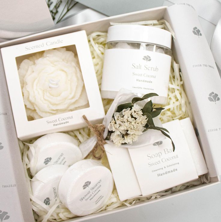 an open box containing soaps, body scrubs, and flowers on the table