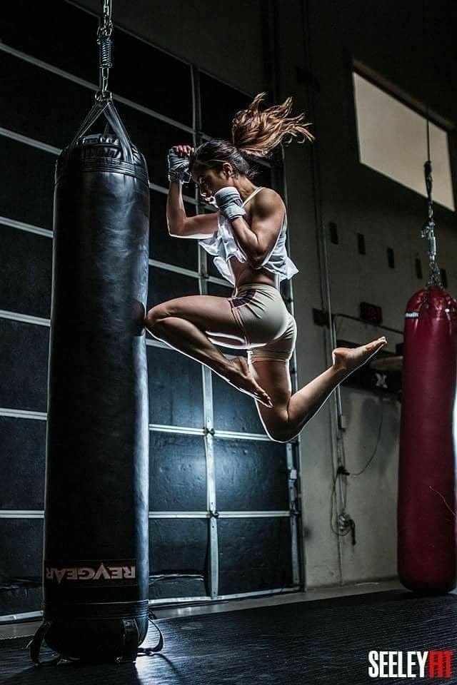 a woman jumping in the air near a punching bag