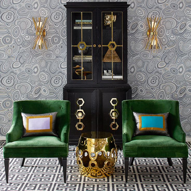 two green chairs sitting next to each other in front of a black and gold cabinet