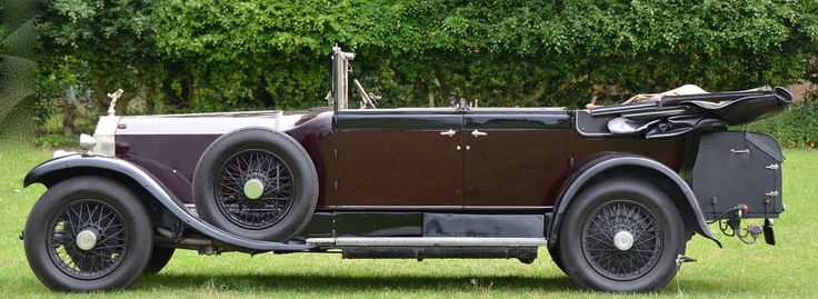 an old model car parked in the grass