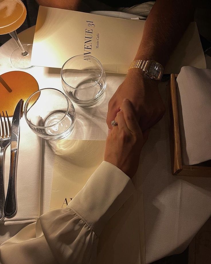 two people sitting at a table holding hands