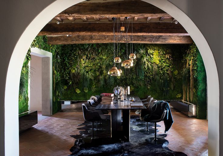 a dining room with an archway leading to the kitchen and sitting area is decorated in green foliage